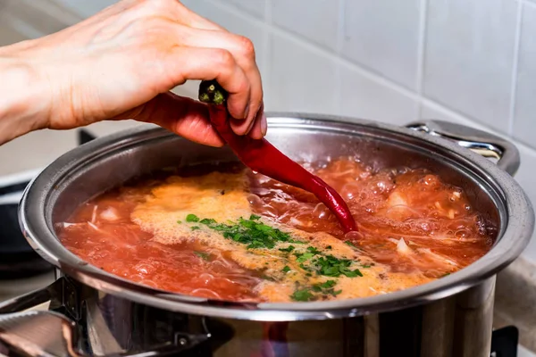 Adding chili pepper to borscht in saucepan close — Stock Photo, Image