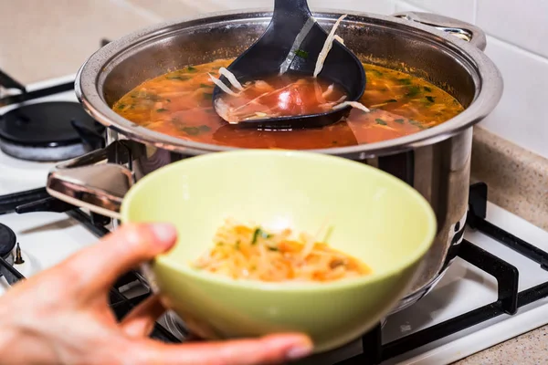 Рука наливает борщ или красный овощной суп в миску — стоковое фото