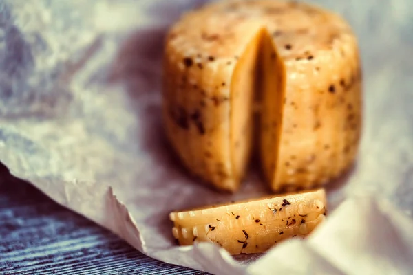 Rustic cheese with herbs on paper background — Stock Photo, Image