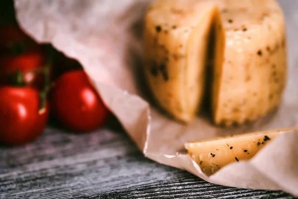 Сыр сельский с травами на бумаге и помидорах — стоковое фото