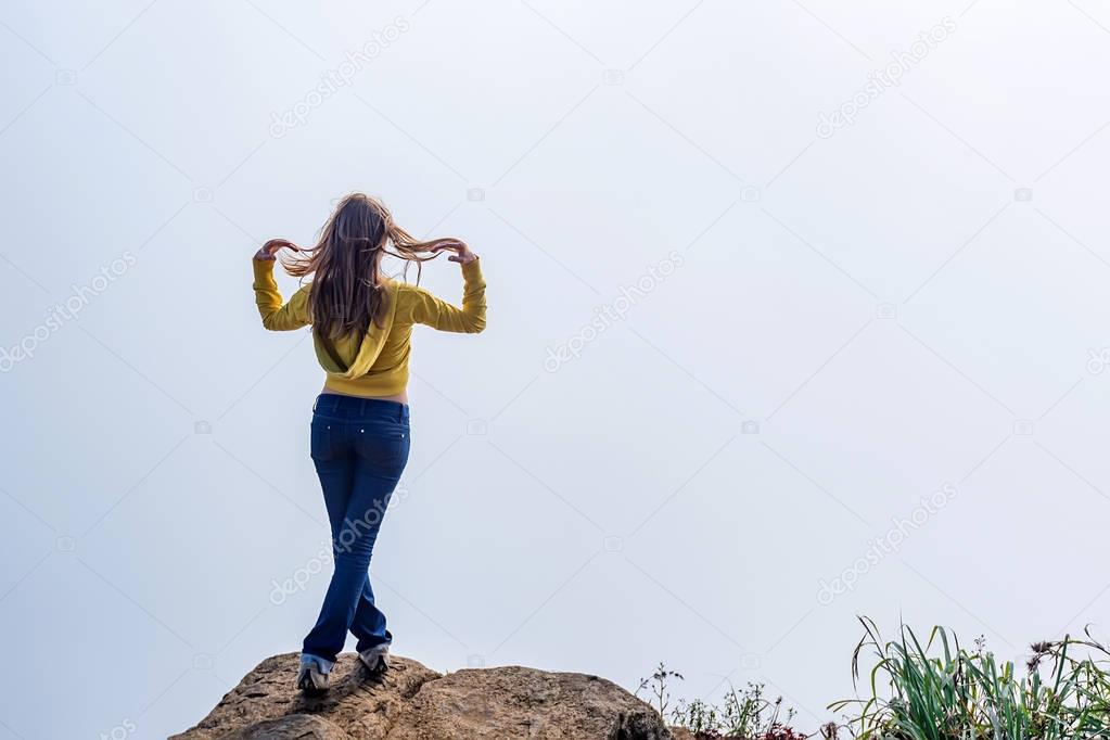 Woman stands on the edge of sheer cliff