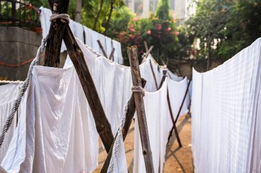 White sheets hang on ropes in Indian street clipart