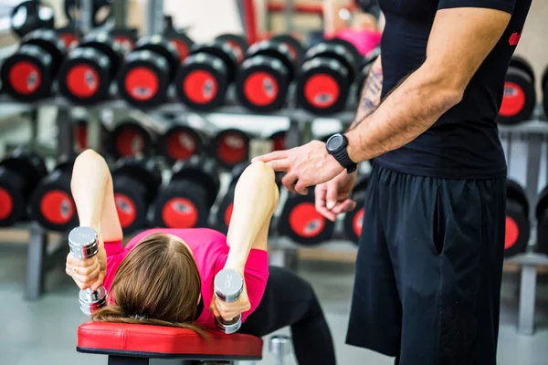 Mujer joven entrena tríceps con entrenador en gimnasio — Foto de Stock