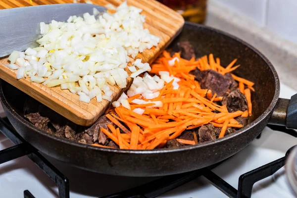 Close up adding chopped onion to beef stew — Stock Photo, Image