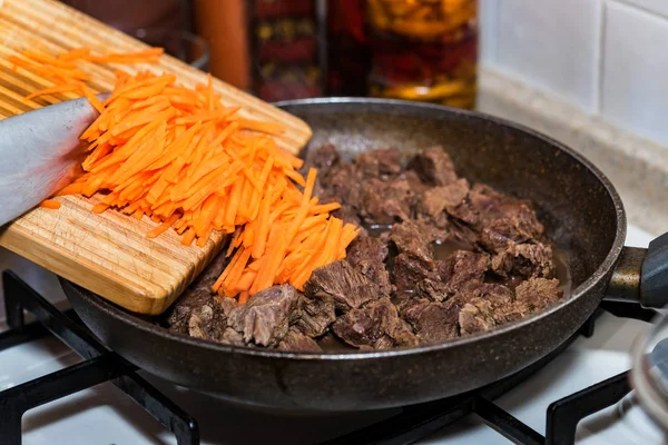 Close up adding chopped carrot to beef stew — Stock Photo, Image