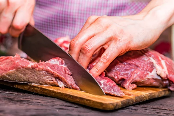 Женские руки режут сырую говядину близко. — стоковое фото