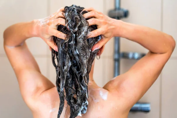 Voltar vista oung mulher cabeça de lavagem com shampoo — Fotografia de Stock