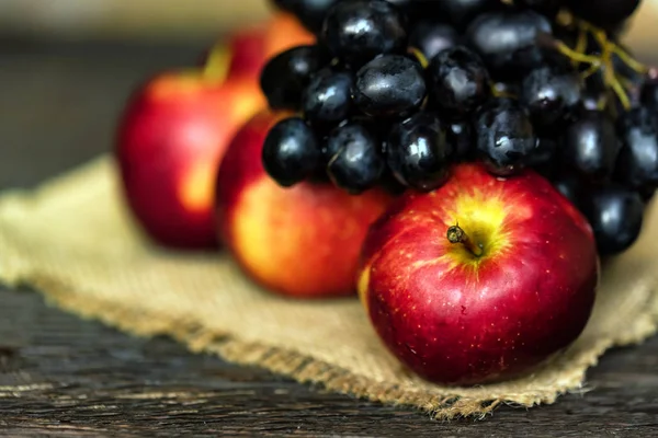 Pommes rouges mûres fraîches et raisins sur une serviette en toile de jute — Photo