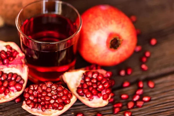 Granadas maduras con vaso de jugo sobre la mesa — Foto de Stock