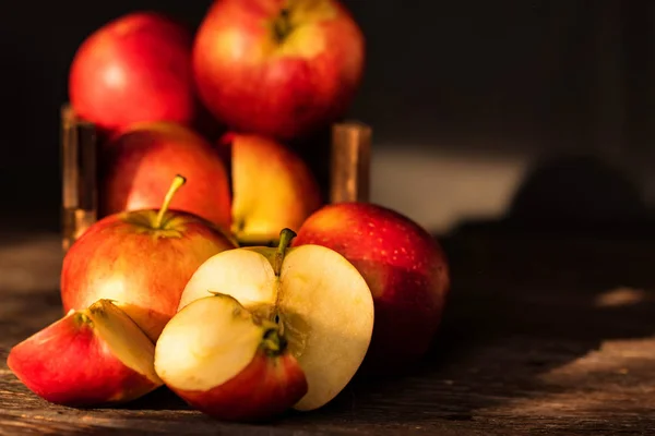 Manzanas enteras y cortadas en mitades sobre superficie de madera — Foto de Stock