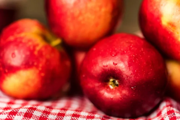 Hela mogna röda äpplen på rutig bordsduk Stäng — Stockfoto