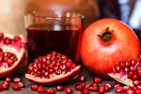 Ripe pomegranates with glass of juice on table — Stock Photo, Image