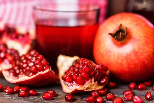Ripe pomegranates with glass of juice on table — Stock Photo, Image