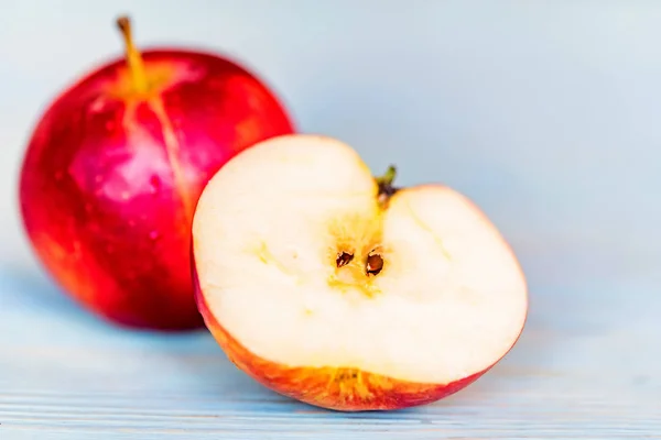 Manzanas enteras y cortadas en superficie de madera azul — Foto de Stock