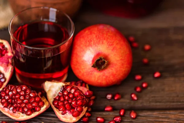 Granadas maduras con vaso de jugo sobre la mesa — Foto de Stock