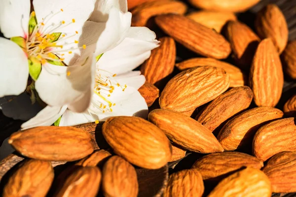 Almonds and white flowers on dark wooden surface