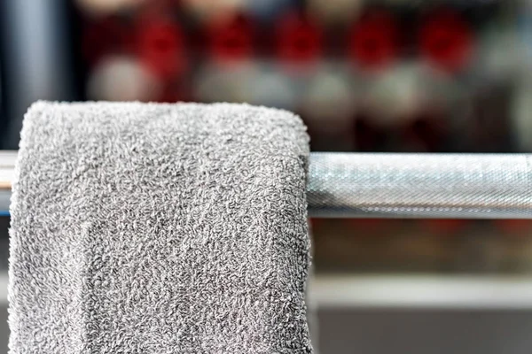 Grey towel hangs on barbell in gym — Stock Photo, Image