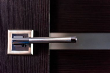 Koyu ahşap kapı üzerindeki modern metal kapı kolu