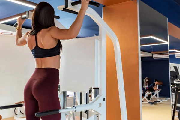 Back view female athlete does back exercises in gym — Stock Photo, Image