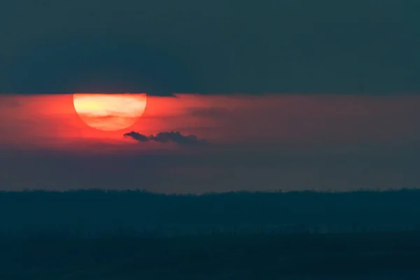 Cielo drammatico al tramonto con nuvole scure e sole rosso — Foto Stock