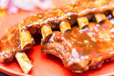 Kırmızı tabakta servis edilen portakal soslu domuz kaburgalarını yakın.