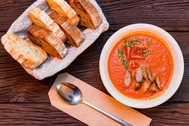 Taze pişmiş domates çorbası sosisli ve ekmekle servis edilir.