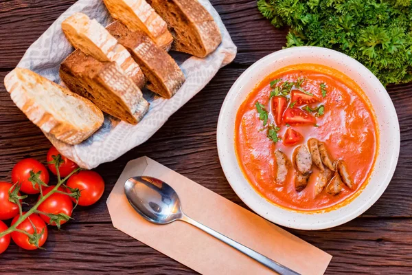 Bord met vers gekookte tomatensoep met worst geserveerd met brood — Stockfoto