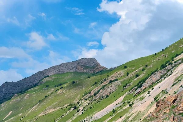 Rocas y hierba verde en las montañas del Cáucaso Norte en otoño en un día soleado — Foto de Stock