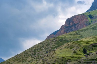 Sonbaharda güneşli bir günde Kuzey Kafkasya dağlarında kayalar ve yeşil çimenler