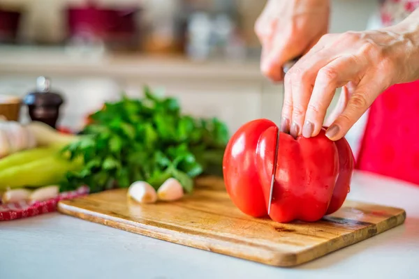 Female hand with knife cuts bell pepper in kitchen. Cooking vegetables — Stock Photo, Image