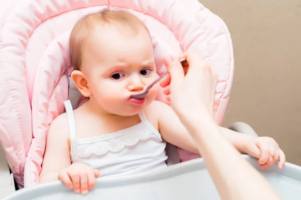 Alimentando bonito bebê menina no carrinho com colher — Fotografia de Stock