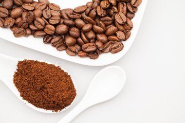 Beyaz kahve kupa, kahve plaka ve çay kaşığı kahve çekirdekleri ve kahve tozu ile