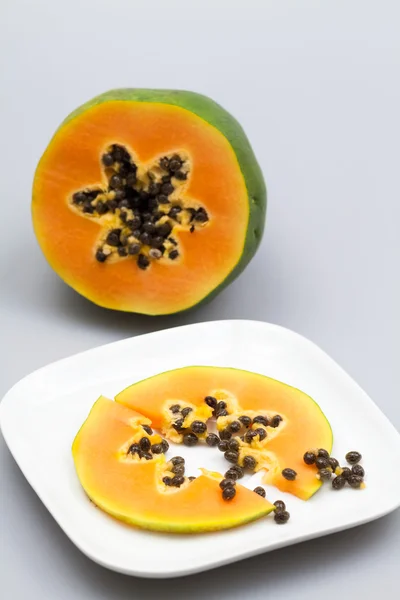 Papaya fruit - half and slice with seeds and light grey background — Stock Photo, Image