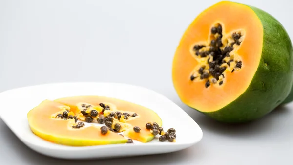 Papayafrucht - halb und in Scheiben geschnitten mit Kernen und hellgrauem Hintergrund — Stockfoto