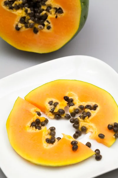 Papaya fruit - half and slice with seeds and light grey background — Stock Photo, Image