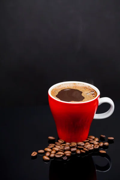 Taza roja de café con granos de café y fondo oscuro — Foto de Stock