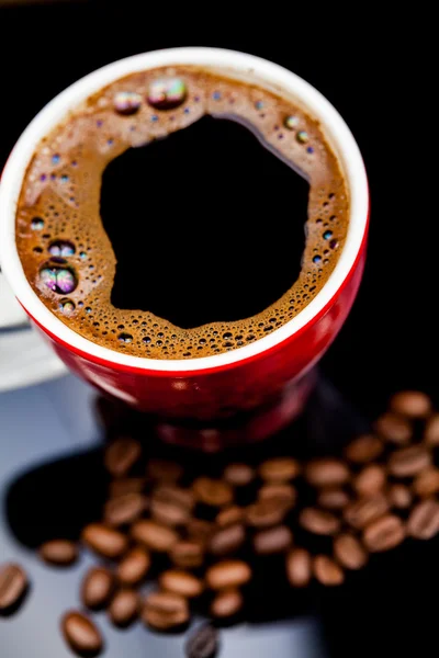 Taza roja de café con granos de café y fondo oscuro — Foto de Stock