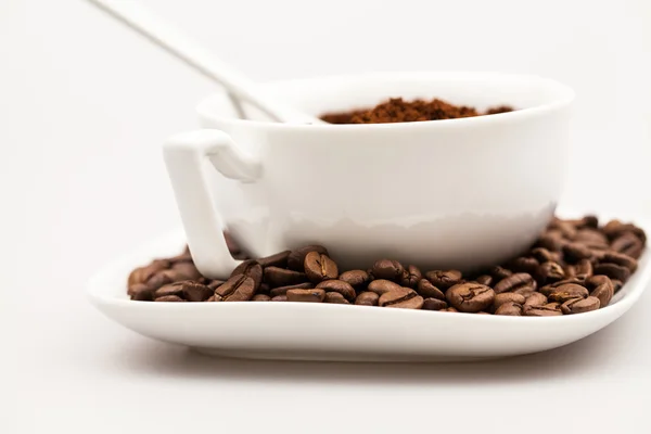 White coffee cup, coffee plate and teaspoon with coffee beans and coffee powder — Stock Photo, Image