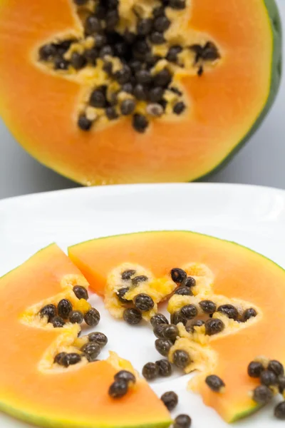 Papaya fruit - half and slice with seeds and light grey background — Stock Photo, Image