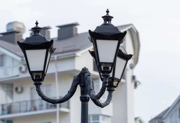 Black street lamp on a background of the house.