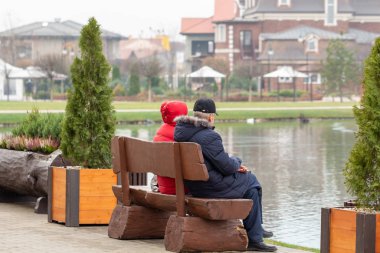 Yaşlı insanlar göldeki banklarda oturuyorlar..