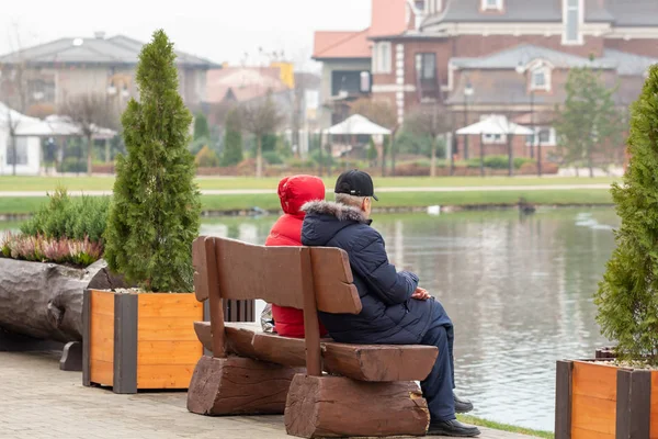 Yaşlı insanlar göldeki banklarda oturuyorlar..