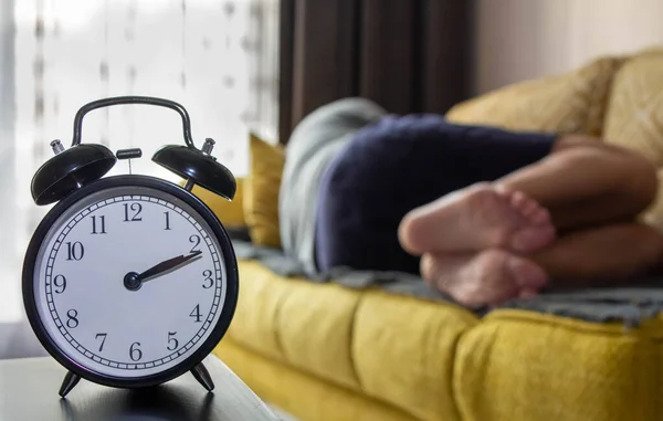 Uyuyan bir adamın arka planında alarmlı saat..