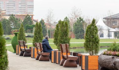 Bir adam gölün yanındaki bankta oturuyor..