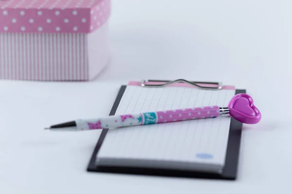 Not defteri ve kalbi olan pembe bir kalem. Pembe renkte kompozisyon.