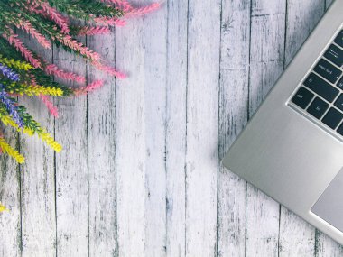 Ahşap bir masada, bir demet lavantanın yanında dizüstü bilgisayar. Yukarıdan görüntüle.