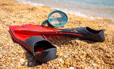 Kırmızı yüzgeçler ve maske deniz kenarında kumlara uzanıyor..