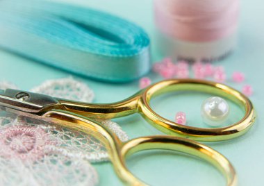 Makas, dantel, boncuk. Pembe ve turkuaz renkte kompozisyon.