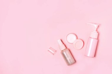 Pembe arka planda kozmetik şişe kapları.
