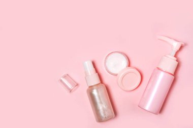 Pembe arka planda kozmetik şişe kapları.